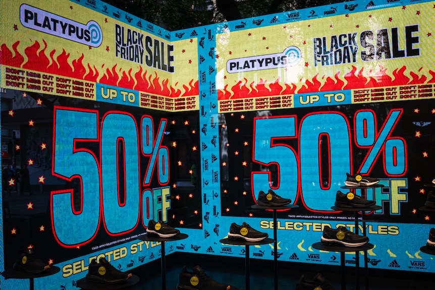 A black sign with blue writing says 50% off