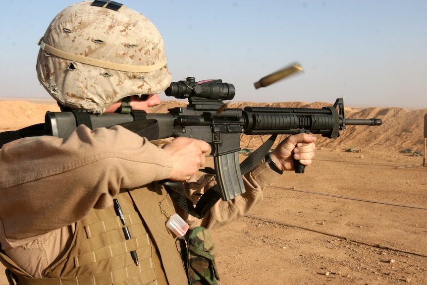 A soldier shoots a gun in Iraq.
