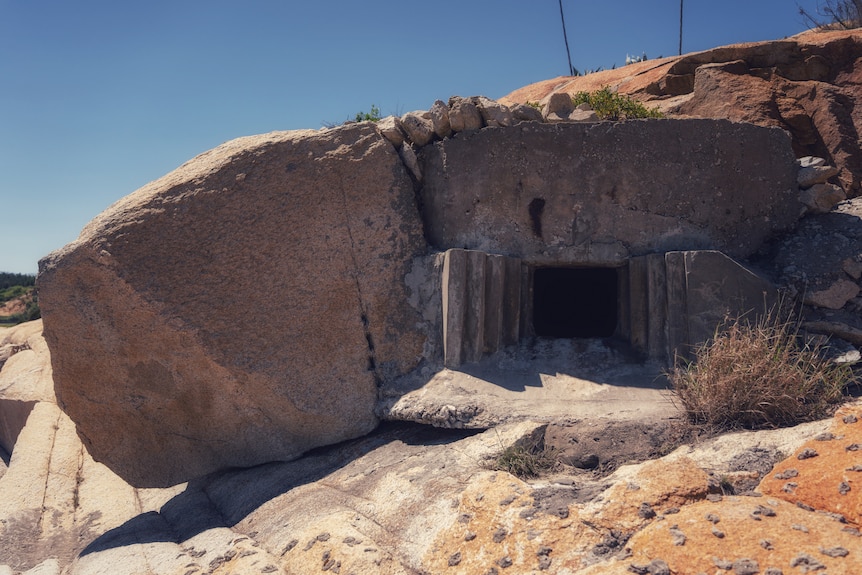 A close up of the opening to a bomb shelter in a rock.