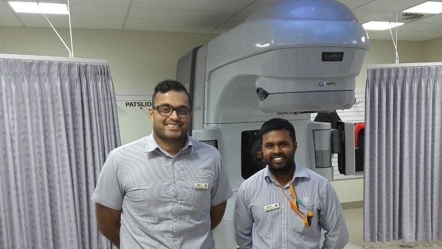 two men stand in front of medical imaging equipment