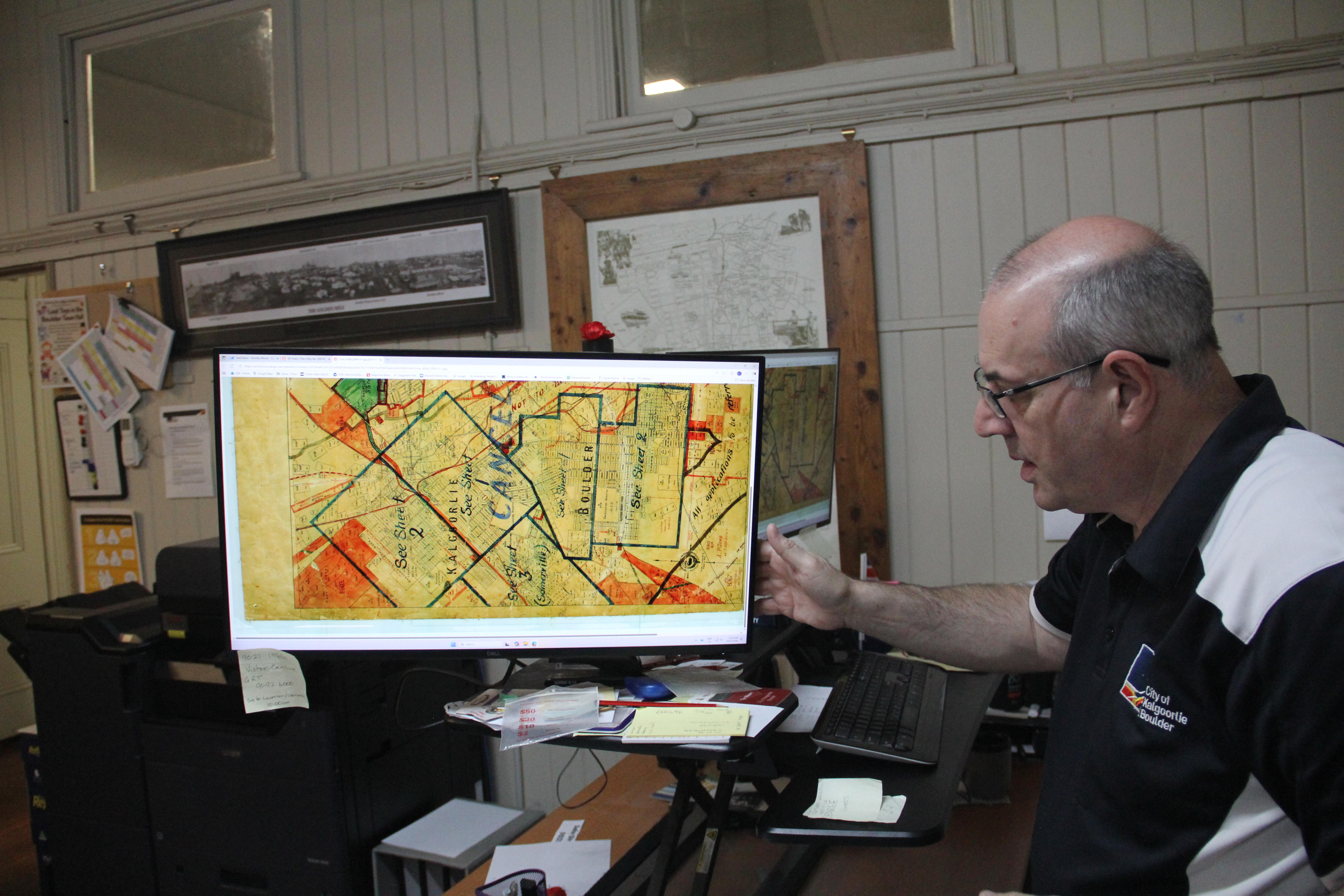 Un hombre con gafas señala una tarjeta amarilla en una pantalla. 