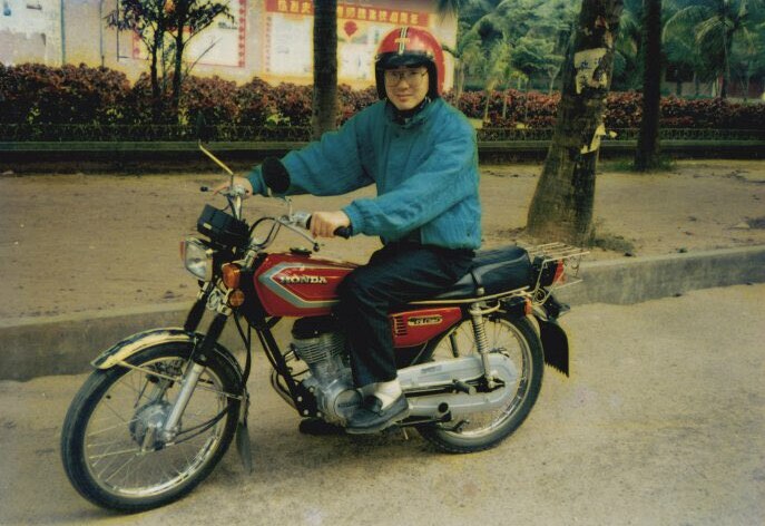 A young Chinese man on a bicycle.