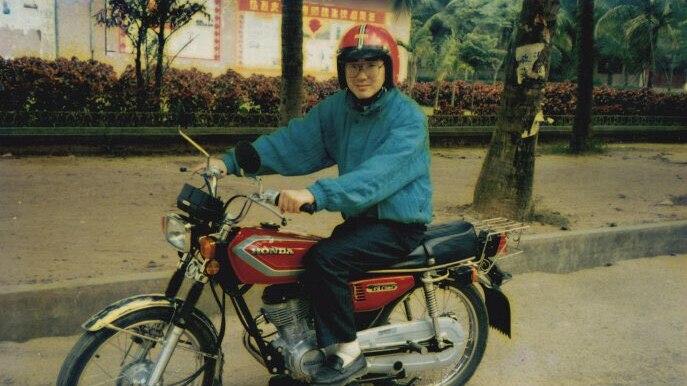 A young Chinese man on a bicycle.