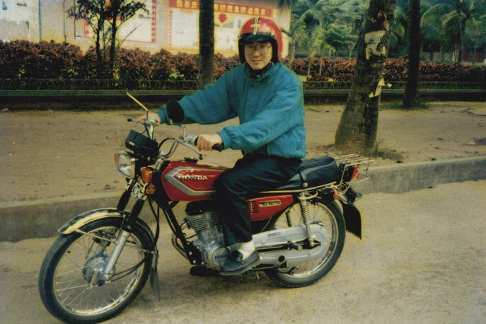 A young Chinese man on a bicycle.