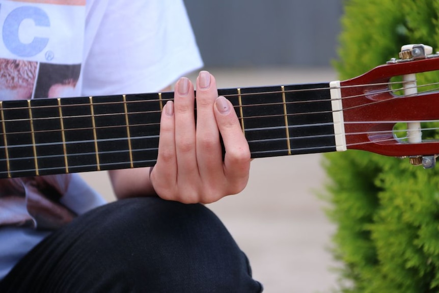 A close up of a person's fingers on the strings of a guitar