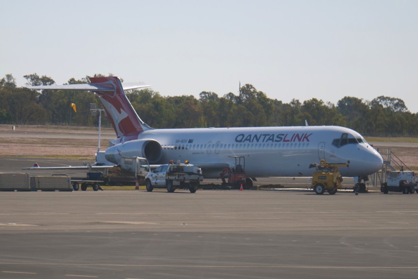 Un avión sentado en la pista del aeropuerto con equipo a su alrededor