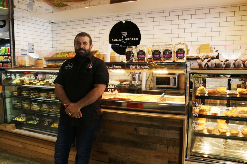 Man stands in front of hot food stand inside grocery store.