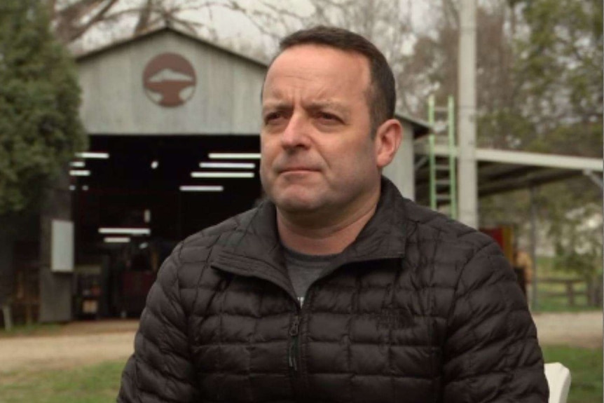 A nice looking man in a black winter jacket gives an interview to a camera.