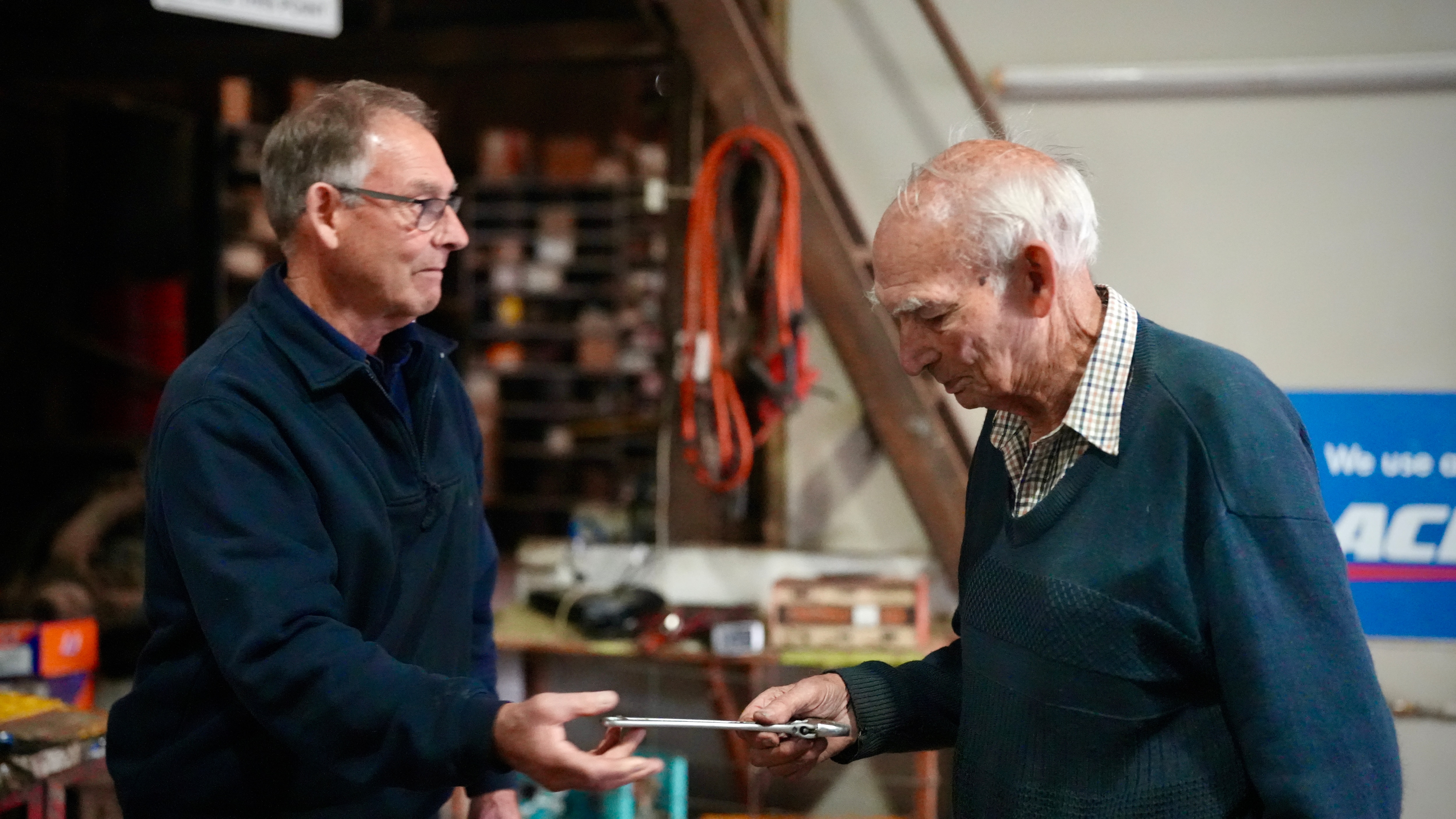 Un hombre de mediana edad pasa junto a su anciano padre Ray y sus herramientas en el taller mecánico.