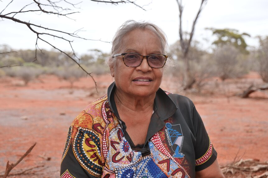 Edie Ulrich dressed in polo t-shirt with Indigenous design in the bush.