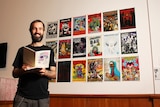 Jeremy Staples stands in front of an exhibition of zines.