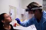 A woman being swabbed in the mouth by a doctor.