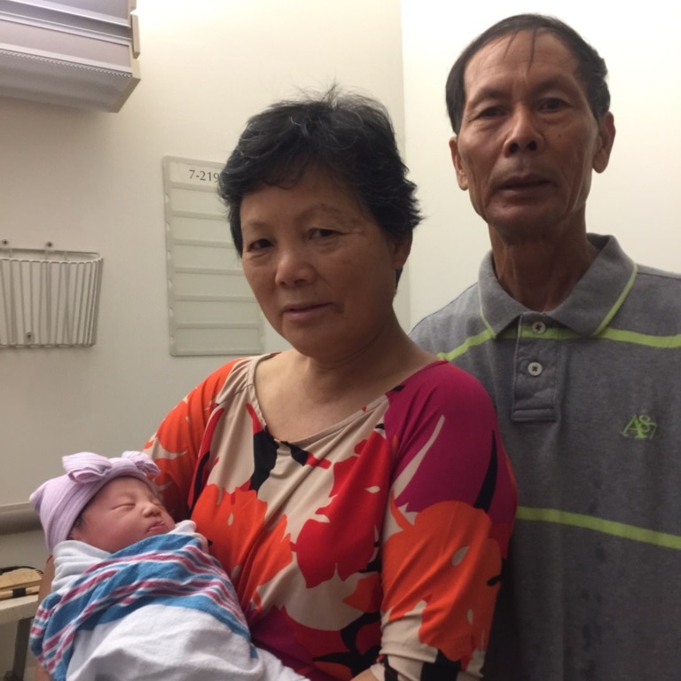 Wei Tang Liu and Xiu Yan Li in hospital. Wei Tang Liu is holding the couple's newborn granddaughter.