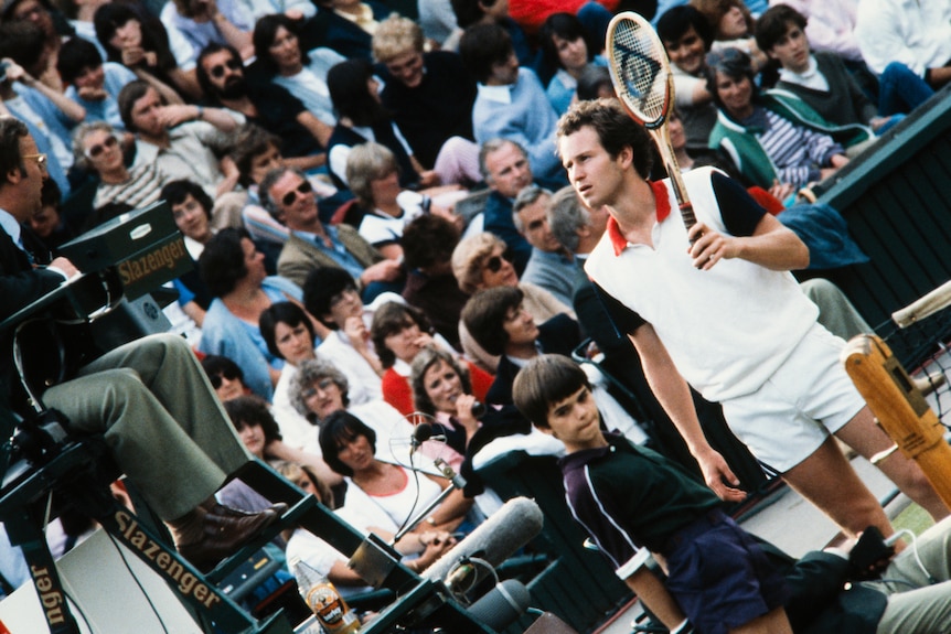 John McEnroe looks up at a chair umpire while holding his racquet