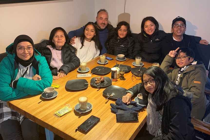 A family of nine people sitting on a dining table