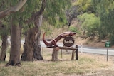 A large wooden goanna statue nailed to a wooden post named Archie.
