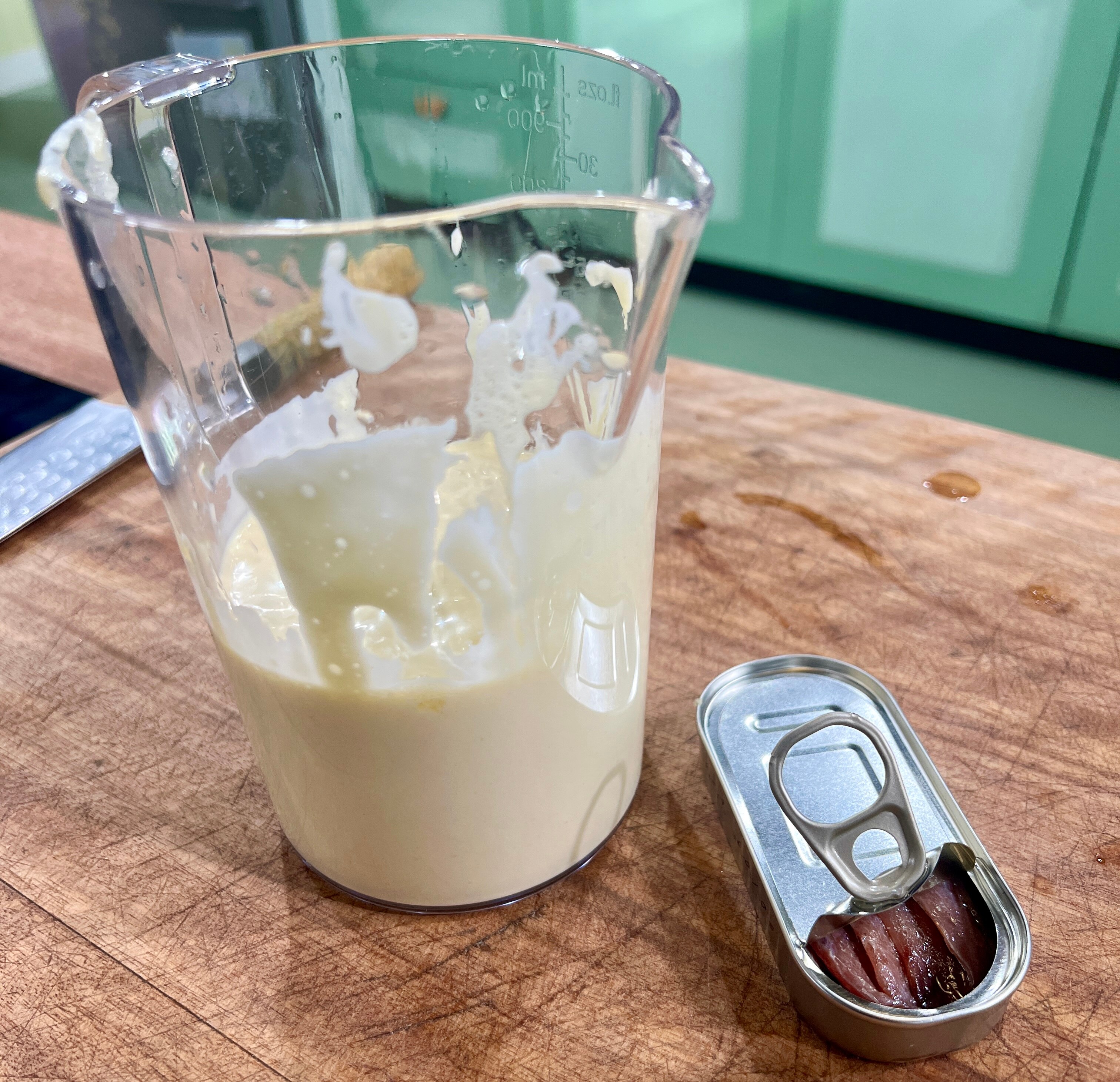 Aioli mix in blender with tin of anchovy's beside on chopping board