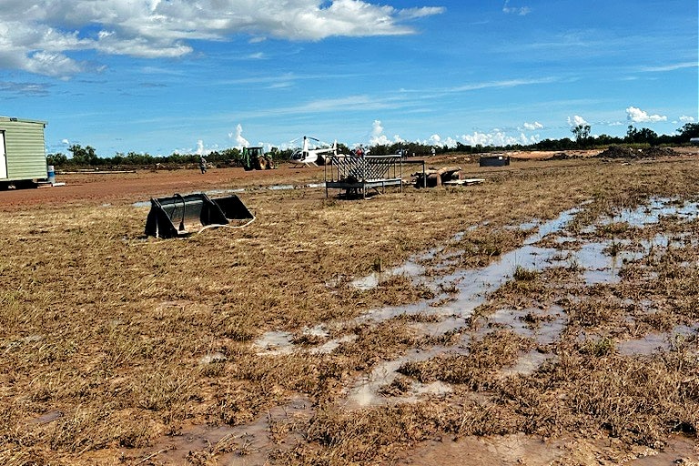 Metal farming equipment debris strewn through the paddock on muddy outback property.