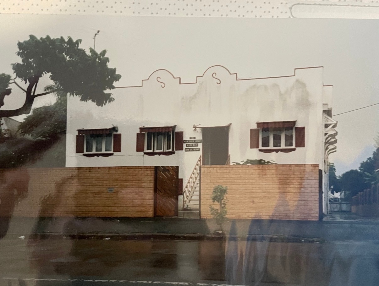 Old photo of white building on a street corner.