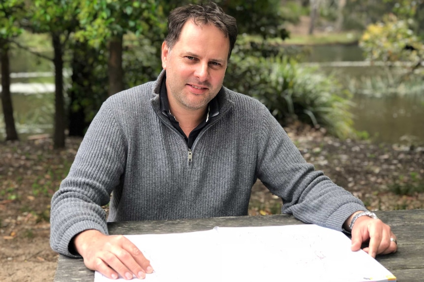 Glen McGarry sits at a park picnic table