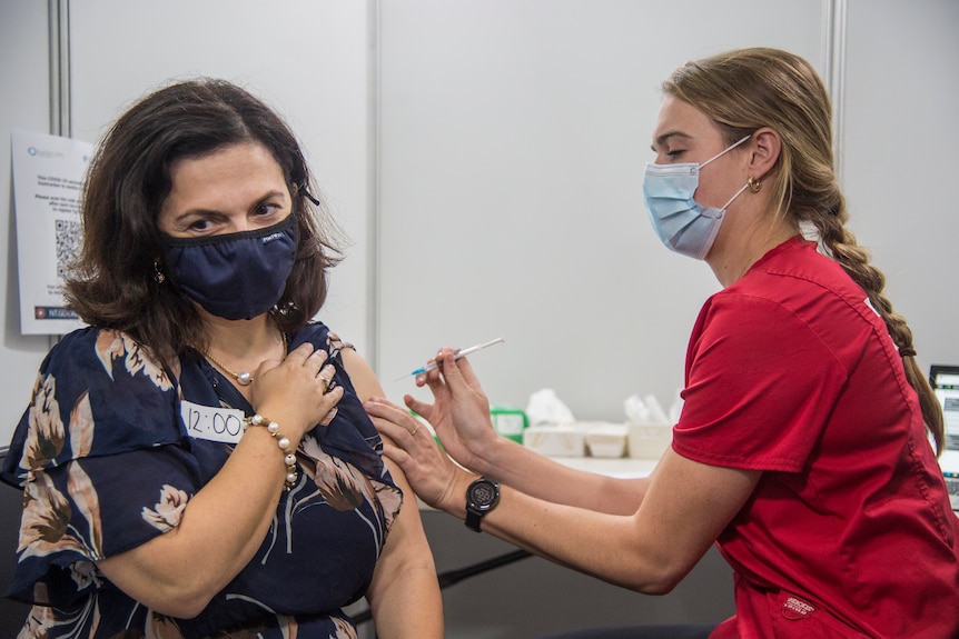 A woman recieves a Pfizer vaccine from a health care worker. 