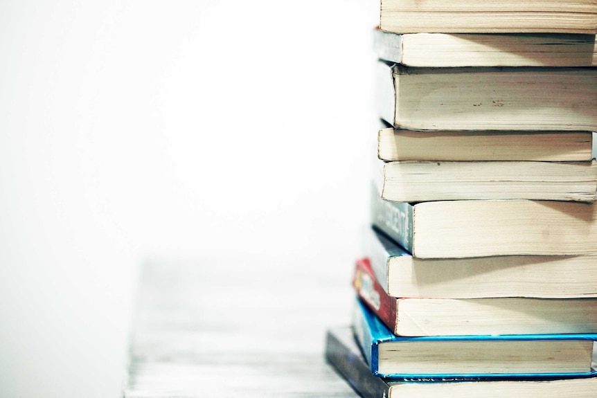 A pile of books sits on a desk to depict the need to upskill before a career change.