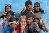 An Australian woman smiling with Indonesian children in a swimming pool.