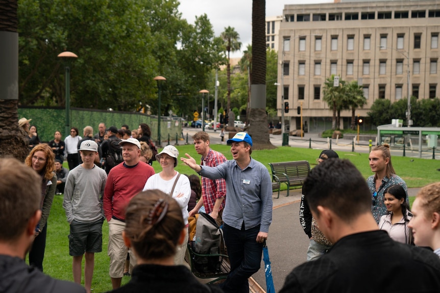 People gathered in a Melbourne CBD park with a tour guide