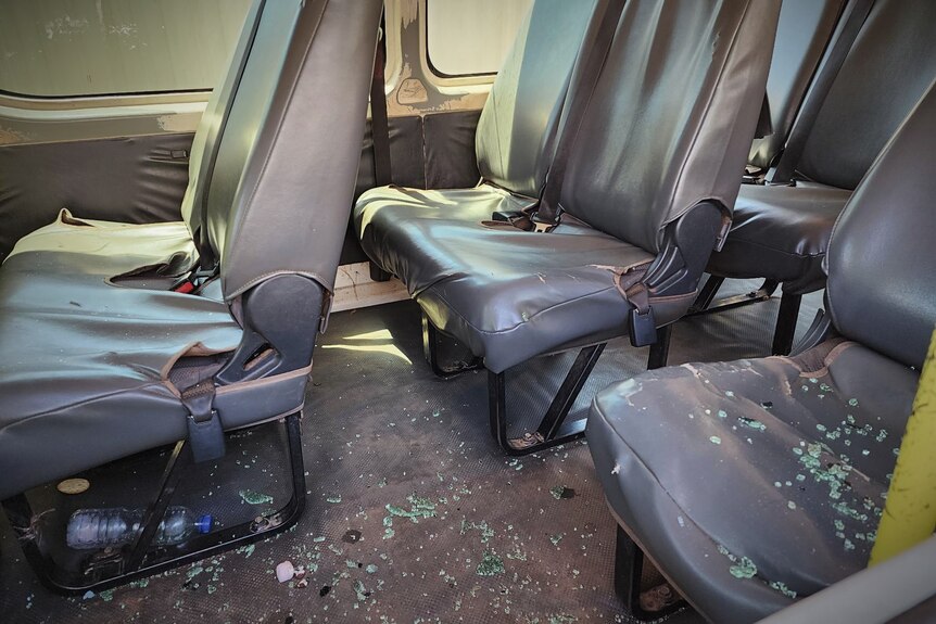 A view inside a bus with multiple seats covered in smashed glass