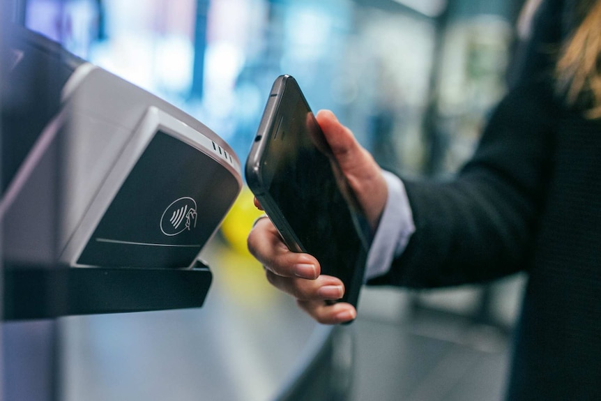 Man uses his phone to pay at a tellar.