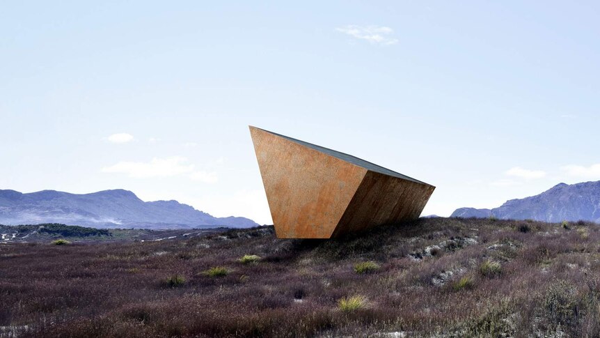 A trapezoid steel shape, rusted, sits cantilevered on a stone outcrop.