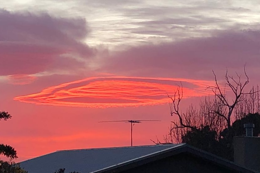 bright pink UFO shaped cloud hangs over home in predawn light
