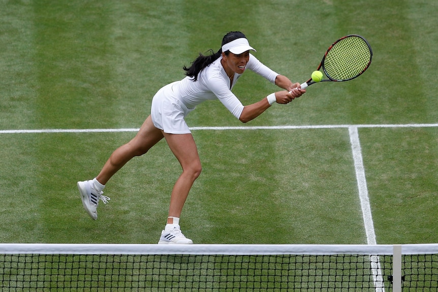 Tennis player Hsieh Su-wei lunges for a tennis ball in front of the net. 