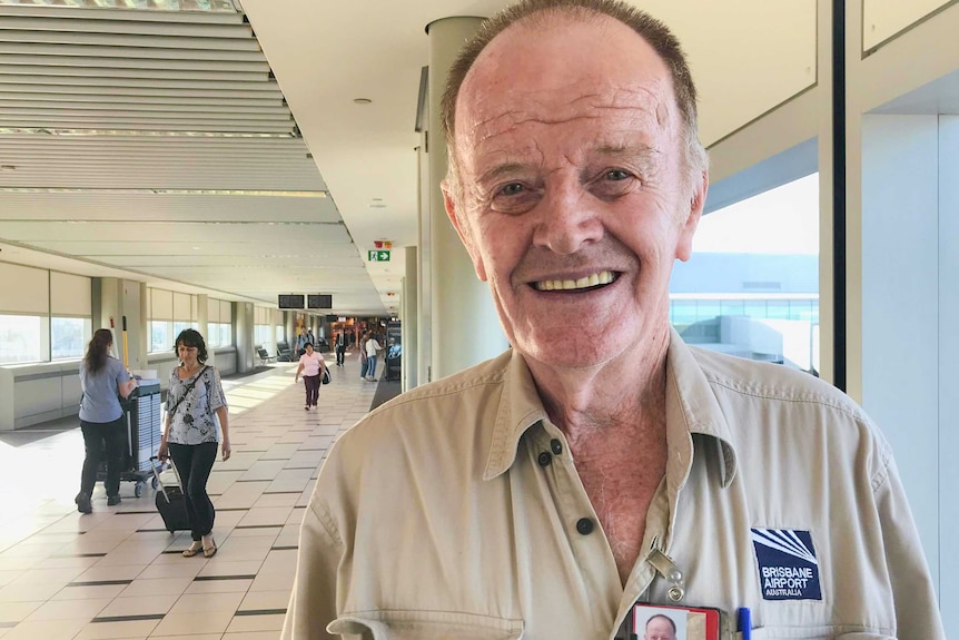 Man standing in an airport smiling.