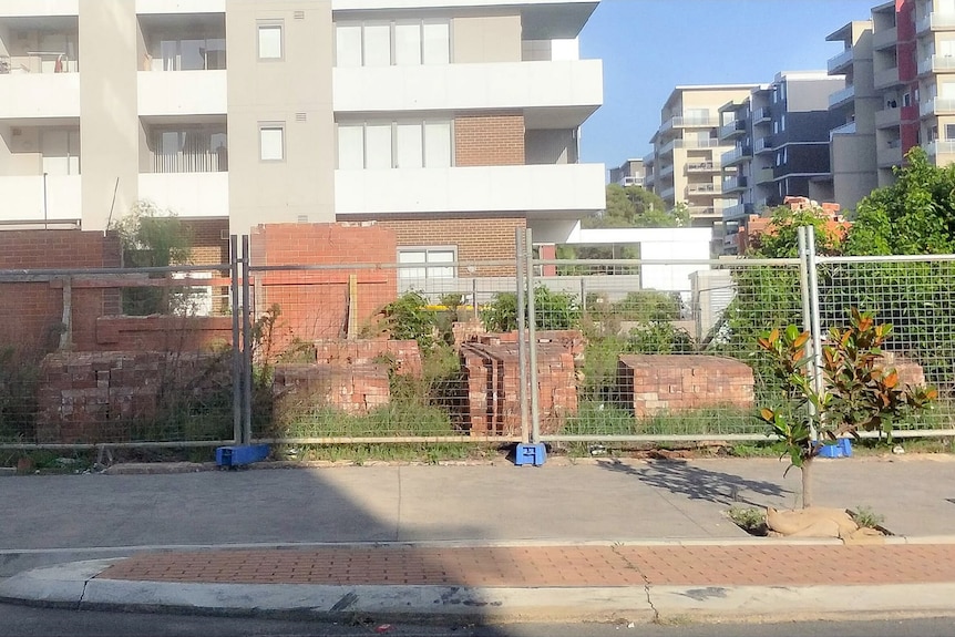 The remains of the heritage site in front of a new apartment building.