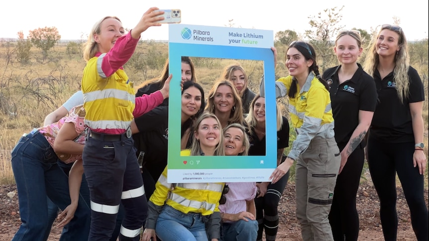 group of women in high-vis pose for a selfie through an instagram post cutout. 