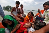 Adults and young children sit on a boat after being rescued from floodwaters.