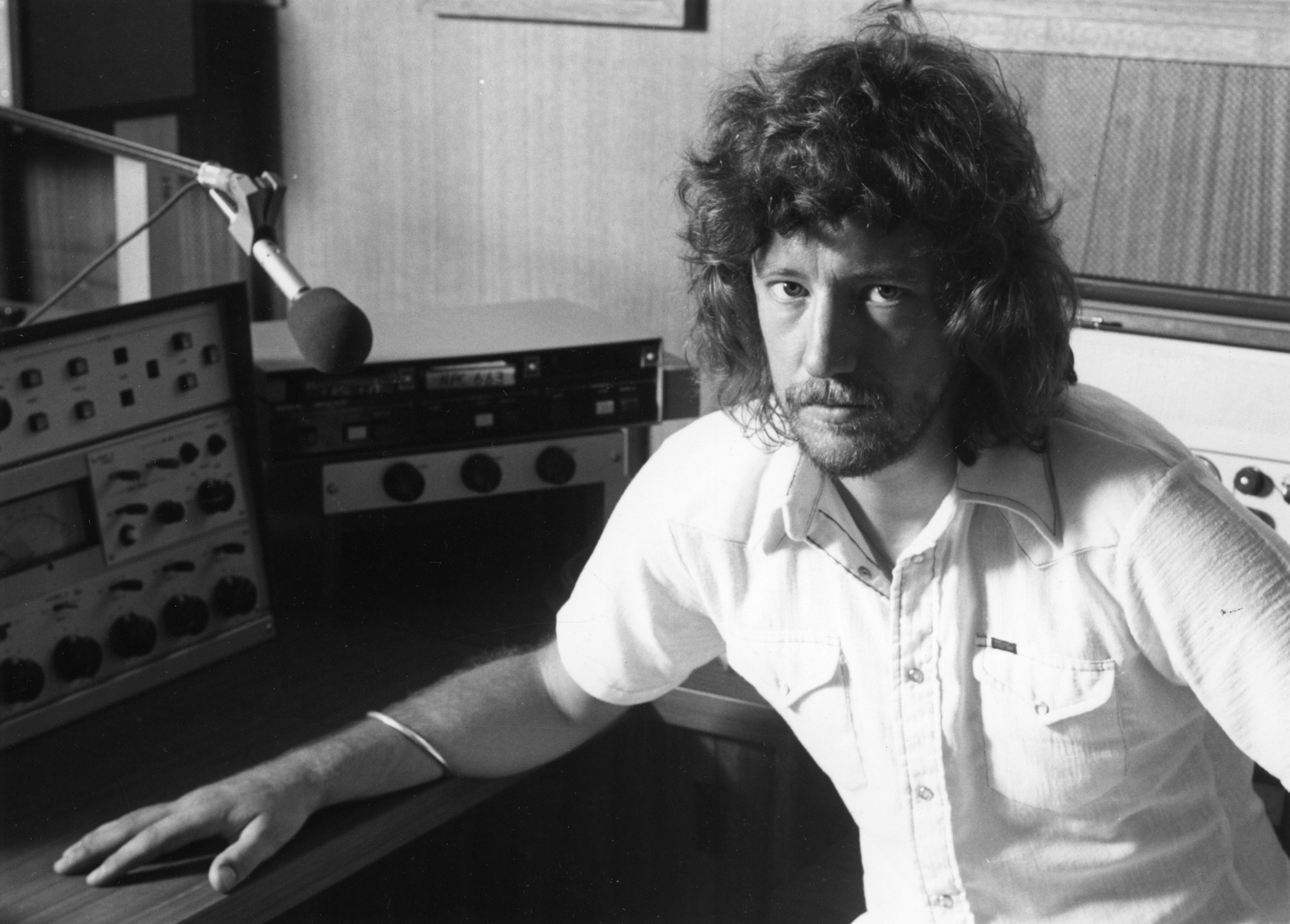 black and white photo portraying a man seated in a radio studio 