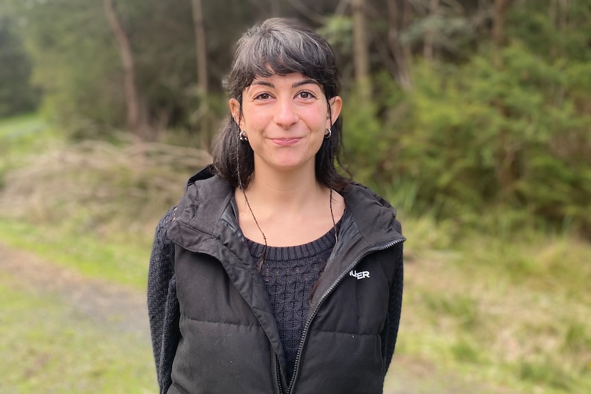 Shari Barmos wearing a puffer vest in a forest area.