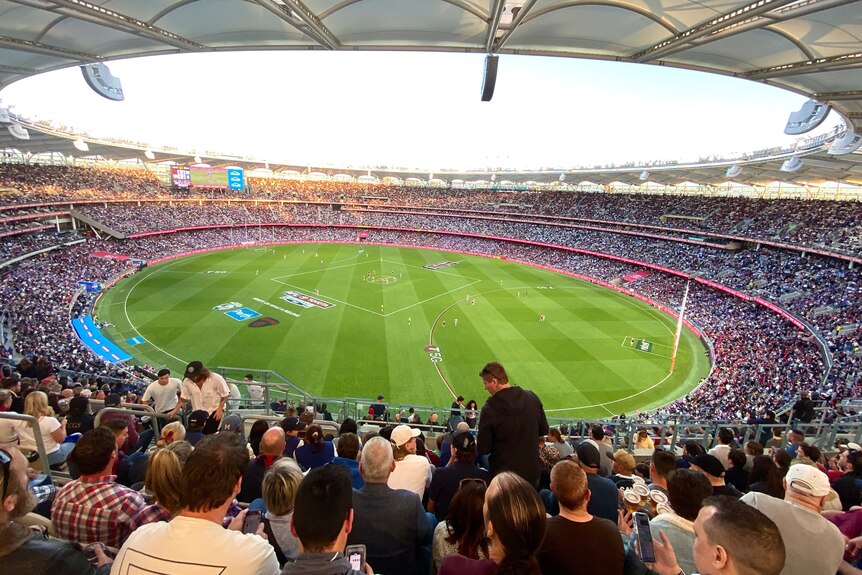 A filled Perth Stadium during the early evening during an AFL game.