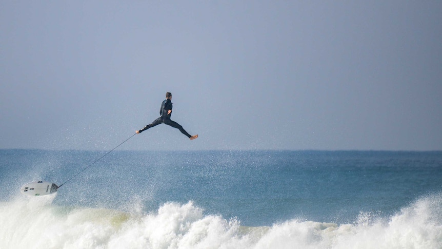 Surfer flies through the air attached to leg rope