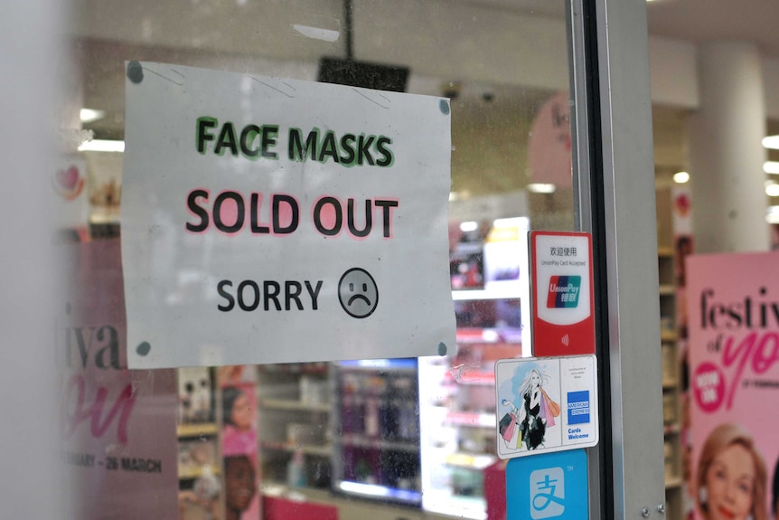 A sign in the window of a chemist saying "Face Masks, Sold Out, Sorry" with a sad face emoji.