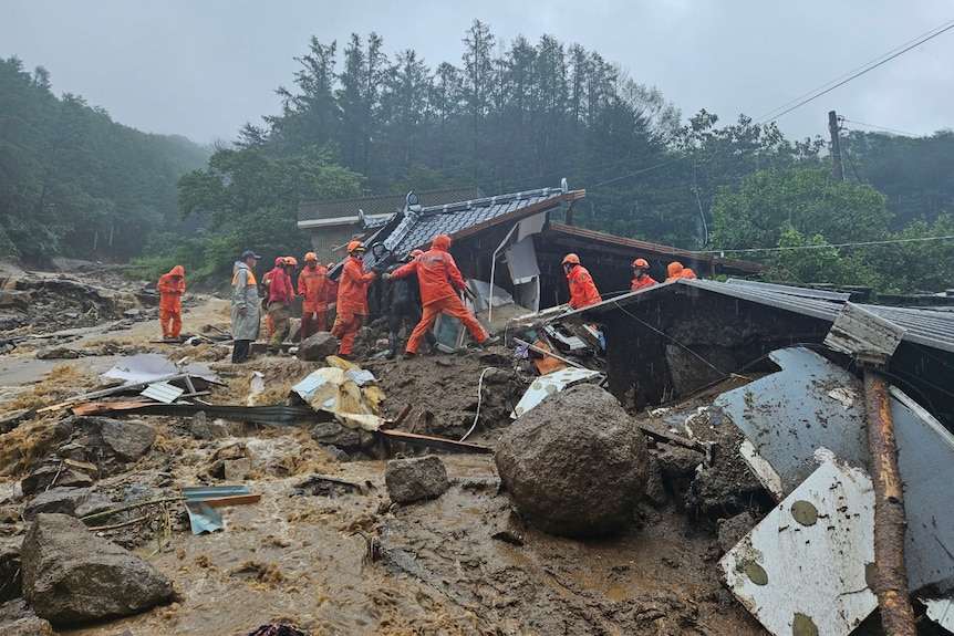 Rescue workers search for people in a house collapsed after a landslide.