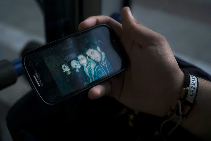 A smartphone screen showing a photo of four Syrian friends.