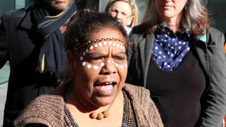 Corina Abraham, with her face painted with dots, with supporters outside court.