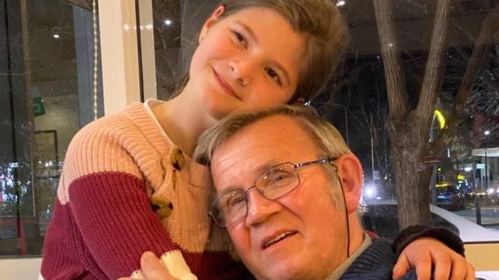 A young girl hugs her grandpa.