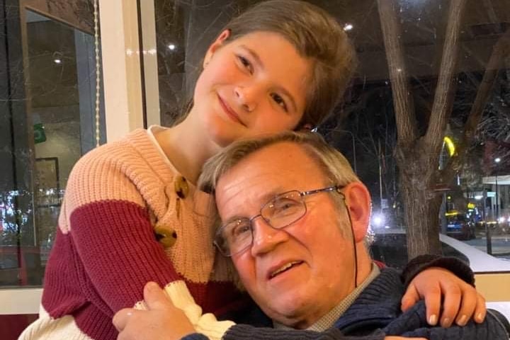 A young girl hugs her grandpa.