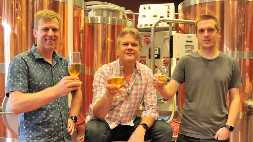 Three scientists each with a glass of beer.