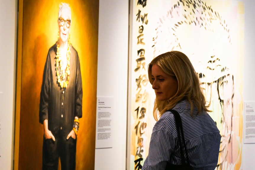 a woman looks at art on the wall inside a gallery