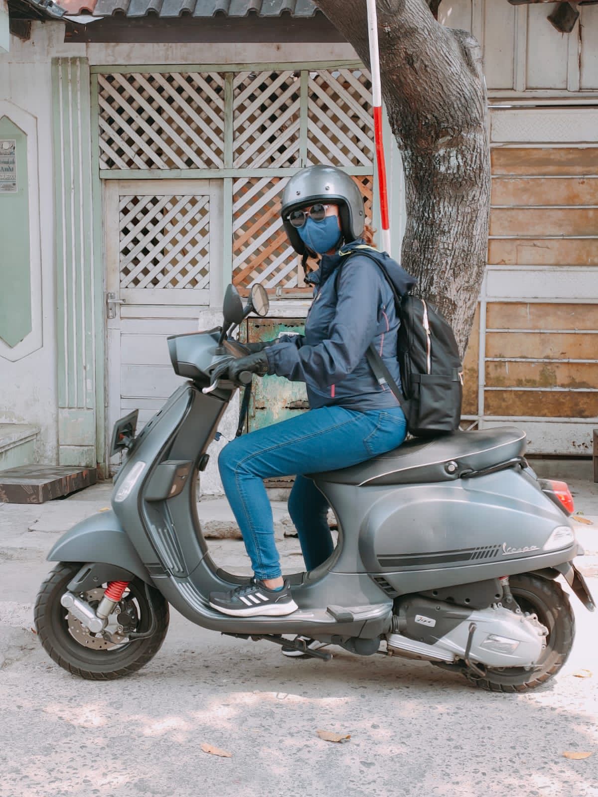 Woman wearing helmet, mask, and glasses on a motorbike.